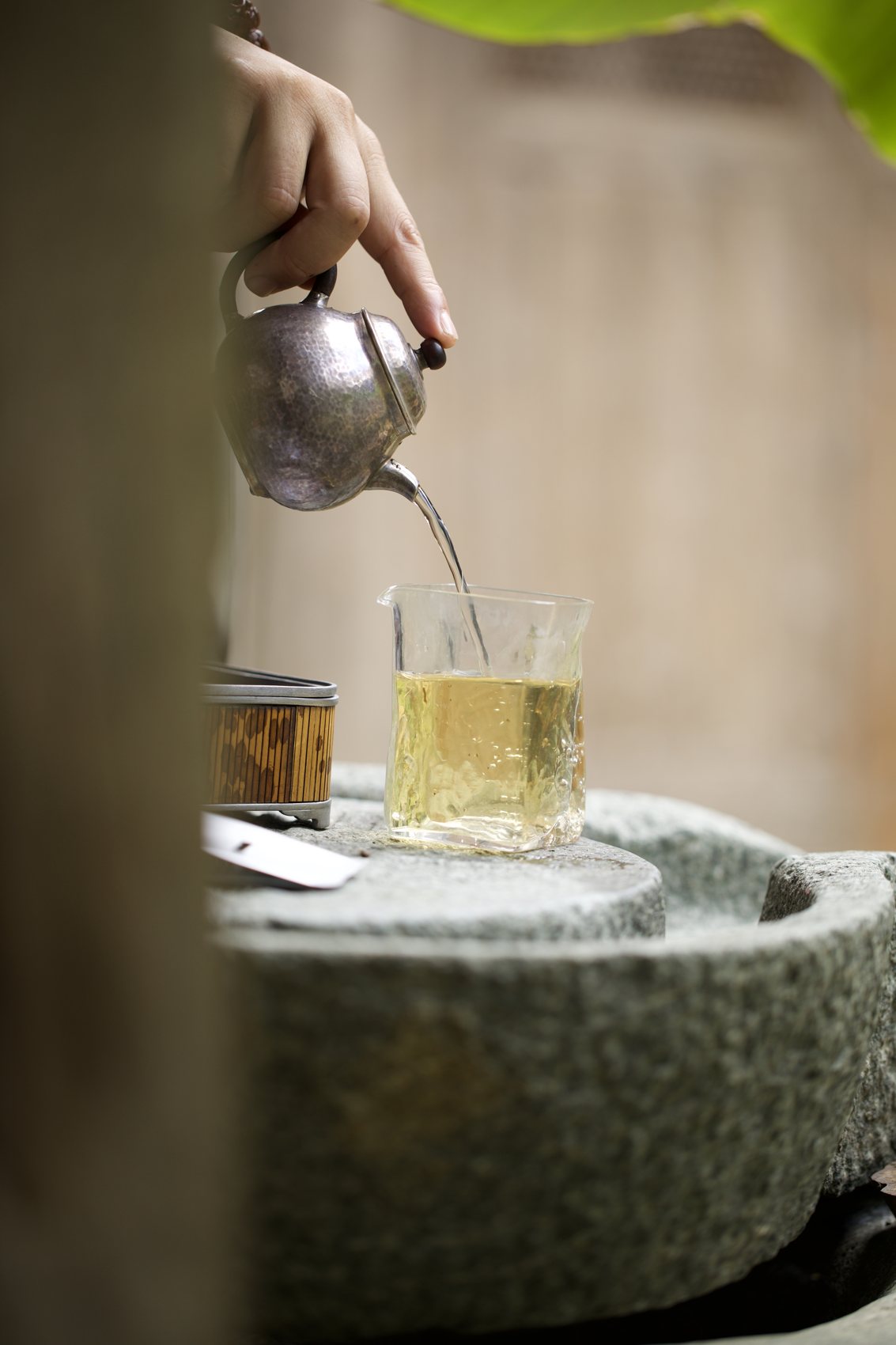 Pouring from a silver kettle into a glass on a stone basin