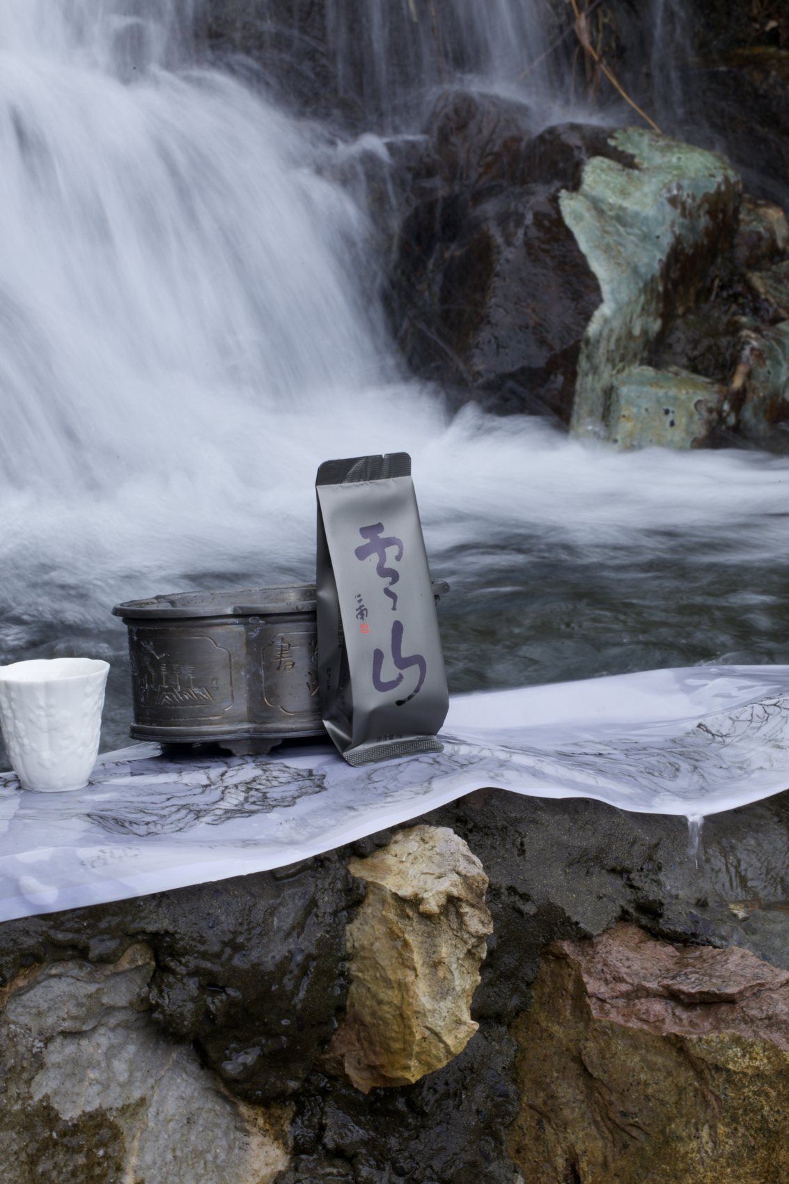 A tea tray laid on the rocks beside the waterfall