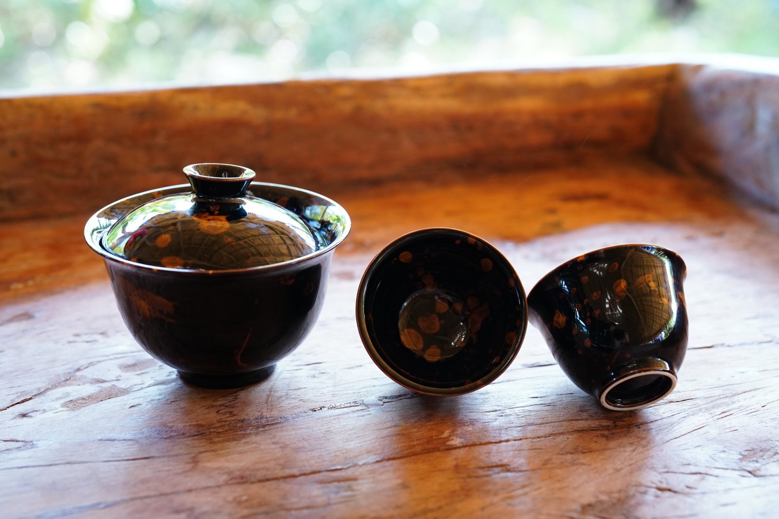 Dark glazed tea bowls on a wooden table