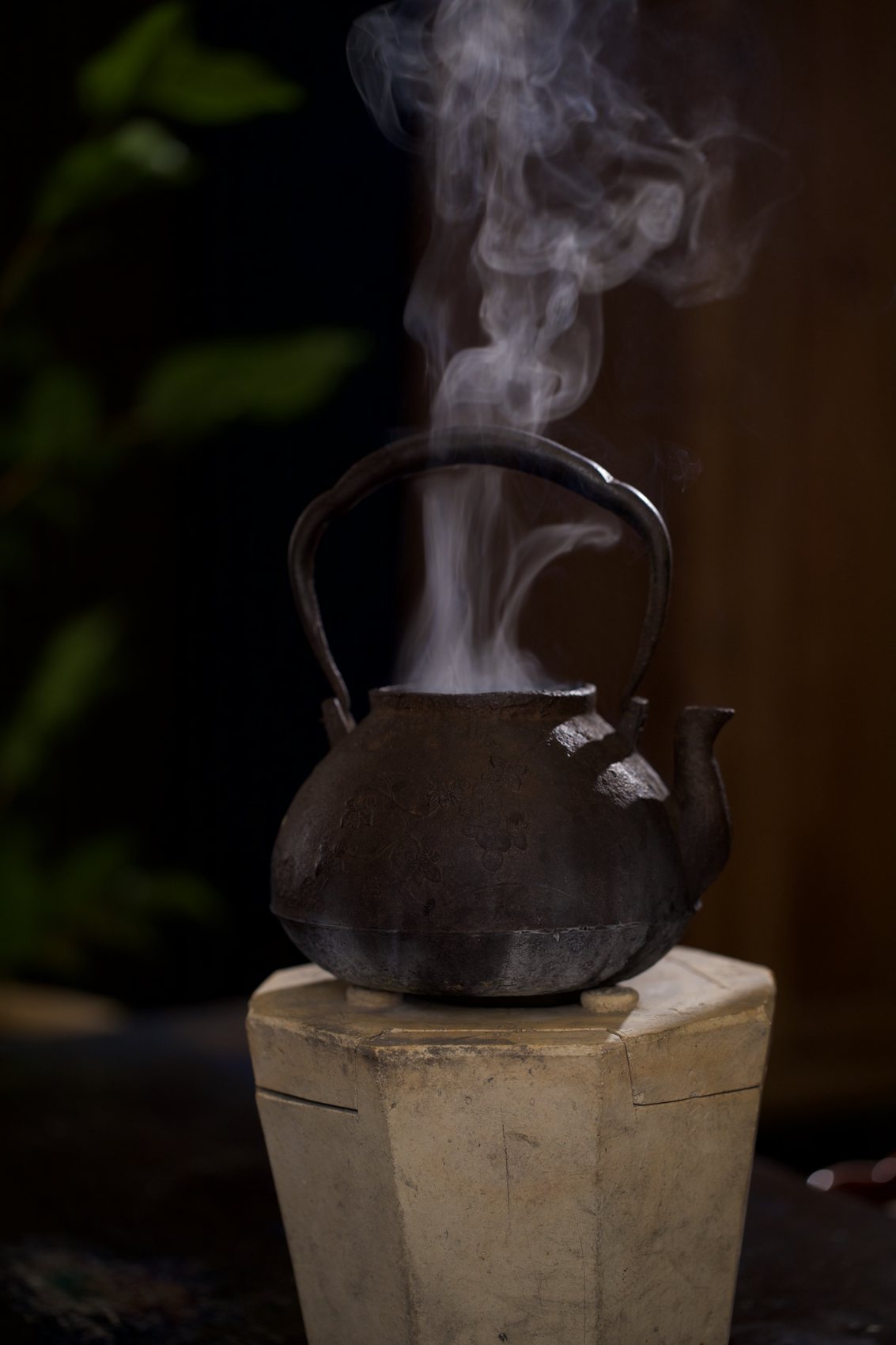 Steam rising from an iron kettle in a dark room