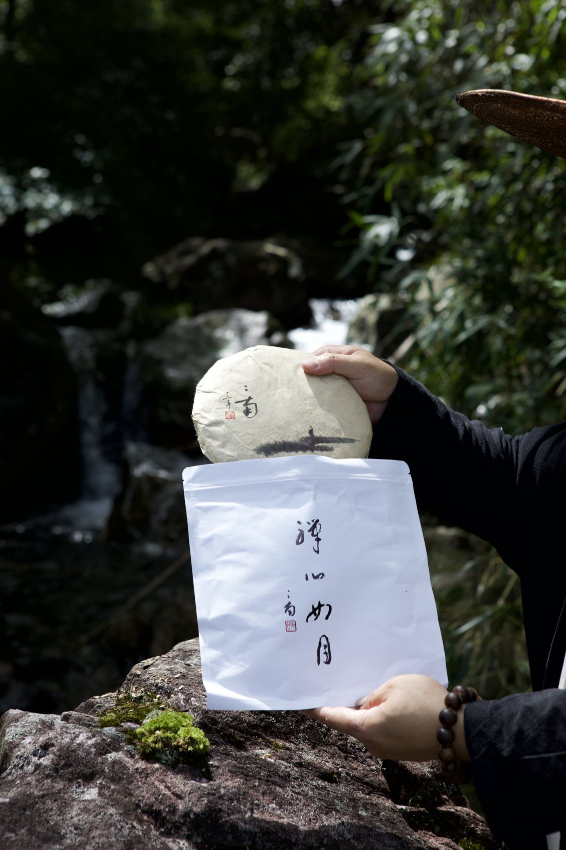 A hand holding a wrapped tea cake above the rocks