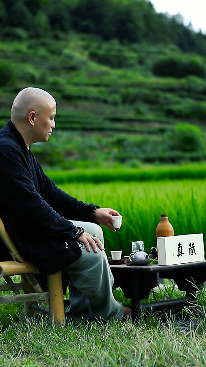 Ernan seated with tea at the edge of the rice field