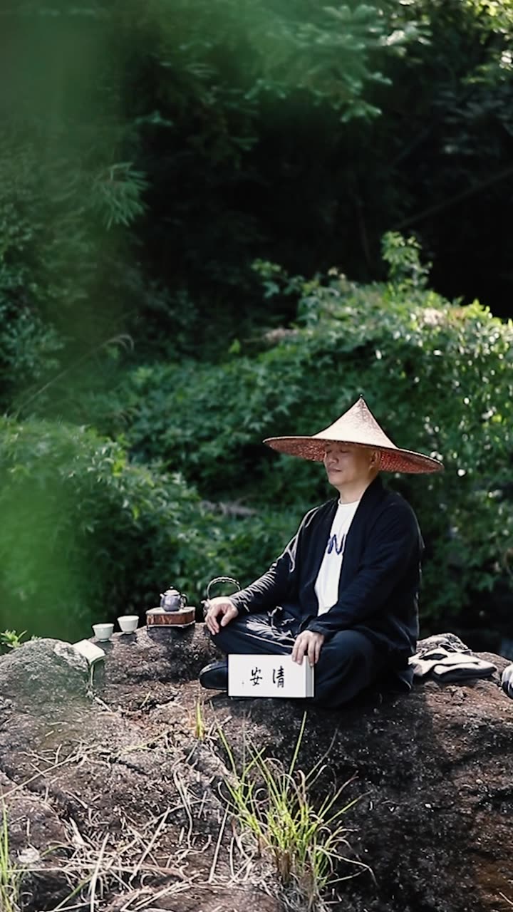 Drinking tea by the creek in a bamboo hat